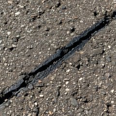 Fine aggregate and a repaired seam in a close-up of road asphalt